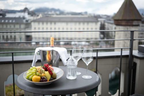 a plate of fruit and wine glasses on a table on a balcony at Hotel Des Alpes in Luzern