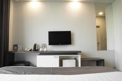 a bedroom with a bed and a tv on a wall at Dreamtel Jakarta in Jakarta