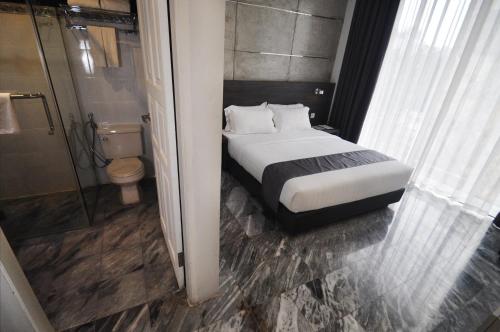 a bedroom with a bed and a shower and a toilet at Dreamtel Jakarta in Jakarta