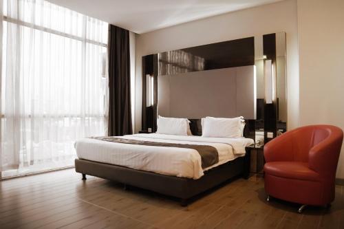 a bedroom with a large bed and a red chair at Dreamtel Jakarta in Jakarta