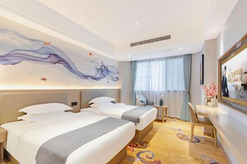 a hotel room with three beds and a painting on the wall at GreenTree Eastern Hotel Chizhou Tonghui Plaza in Chizhou