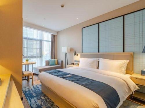a bedroom with a large bed and a living room at Echarm Hotel Hefei West Qilitang Metro Station in Hefei