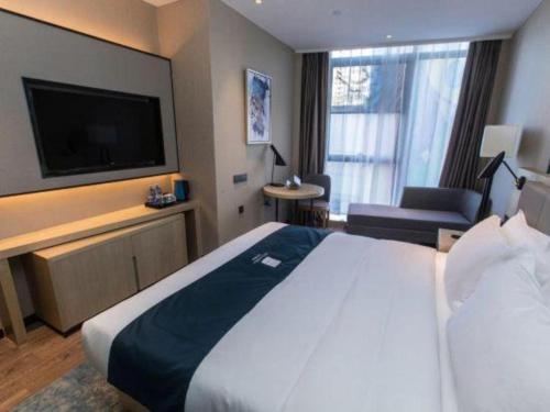 a hotel room with a large bed and a flat screen tv at Echarm Hotel Hefei West Qilitang Metro Station in Hefei
