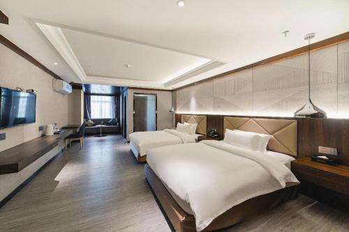 a hotel room with two beds and a flat screen tv at Borrman Hotel Zhongshan Henglan Xiyong in Zhongshan