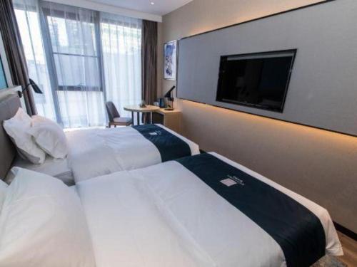 a hotel room with two beds and a flat screen tv at Echarm Hotel Hefei West Qilitang Metro Station in Hefei