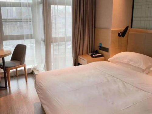 a bedroom with a large white bed and a chair at Echarm Hotel Hefei West Qilitang Metro Station in Hefei