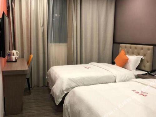 a hotel room with two beds and a desk at Shell Hotel Shanghai Jinshan Wanda Plaza in Nanhui
