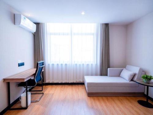 a room with a couch and a desk and a window at GreenTree Inn Express Hebei Tangshan Guyan District Xinguang Road in Tangshan