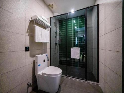 a bathroom with a toilet and a glass shower at GreenTree Inn Express Hebei Tangshan Guyan District Xinguang Road in Tangshan
