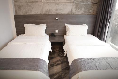 two twin beds in a room with a table at Dreamtel Jakarta in Jakarta