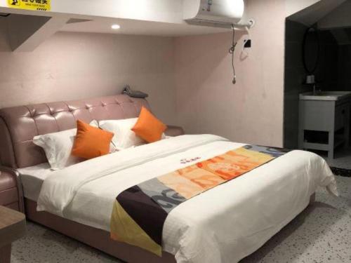a bedroom with a large bed with orange pillows at Shell Hotel Shanghai Jinshan Wanda Plaza in Nanhui