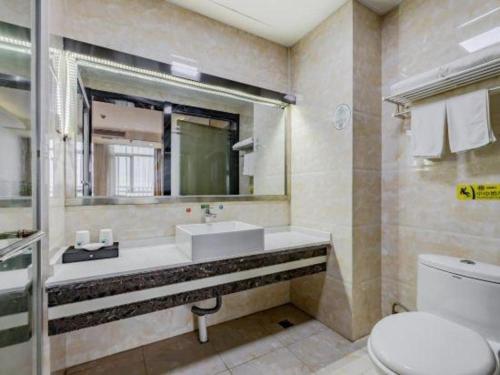 a bathroom with a sink and a mirror and a toilet at GreenTree Inn Anqing Yingbin Dong Road High-Speed Railway Station in Anqing