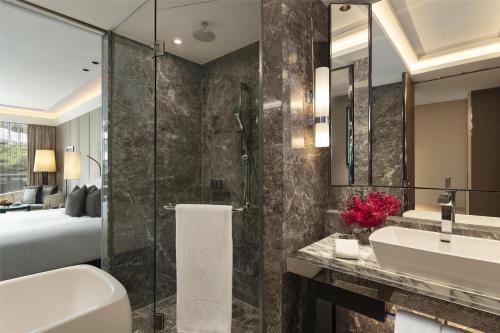 a bathroom with a tub and a sink and a bed at Siam Kempinski Hotel Bangkok in Bangkok