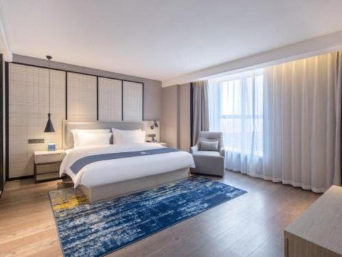 a bedroom with a king sized bed and a chair at Echarm Hotel Nanning the MixC Dongmeng Business District in Nanning
