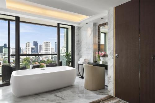 a bathroom with a white tub and a large window at Siam Kempinski Hotel Bangkok in Bangkok