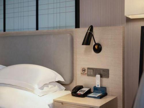 a hotel room with a bed with a phone on a night stand at Echarm Hotel Nanning the MixC Dongmeng Business District in Nanning