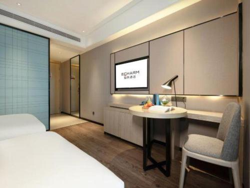 a bedroom with a bed and a desk and a tv at Echarm Hotel Nanning the MixC Dongmeng Business District in Nanning
