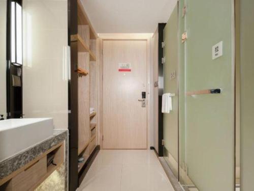 a bathroom with a sink and a toilet and a door at Echarm Hotel Nanning the MixC Dongmeng Business District in Nanning