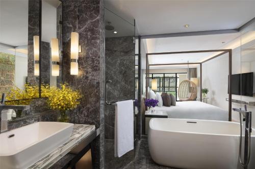 a bathroom with a sink and a tub and a bed at Siam Kempinski Hotel Bangkok in Bangkok