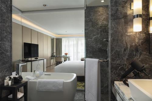 a bathroom with a bath tub and a bedroom at Siam Kempinski Hotel Bangkok in Bangkok