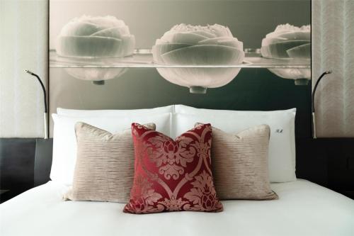 a bed with a red pillow and some plates on a shelf at Siam Kempinski Hotel Bangkok in Bangkok