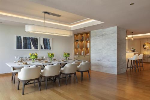 a dining room with a long table and white chairs at Siam Kempinski Hotel Bangkok in Bangkok