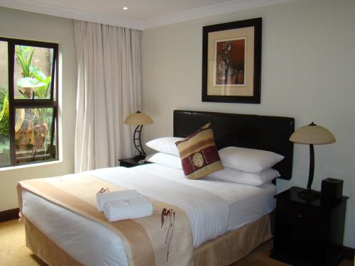 Un dormitorio con una cama grande con sábanas y almohadas blancas. en Zawadi House Lodge, en Arusha