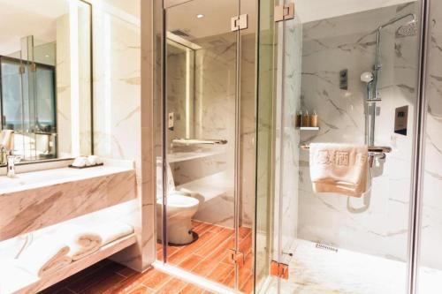 a bathroom with a shower and a toilet and a sink at Borrman Hotel Yunfu Xinxing County Bus Station in Yunfu