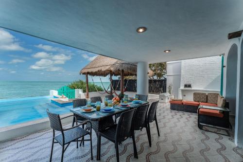 a dining room with a table and chairs and the ocean at La Casa Del Velero, Beachfront in Chicxulub
