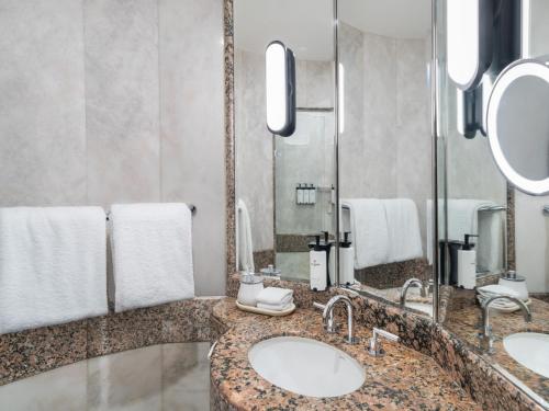 a bathroom with two sinks and a large mirror at Sofitel Sydney Wentworth in Sydney