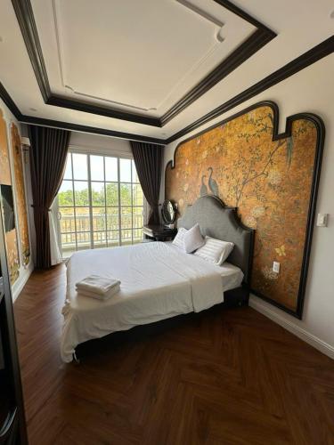 a bedroom with a large bed with a large wall at NOVA WORLD PHAN THIẾT - An VILLA in Bình Tú