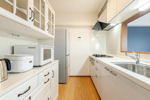 a white kitchen with a sink and a microwave at Jintai House601 in Shiobaru
