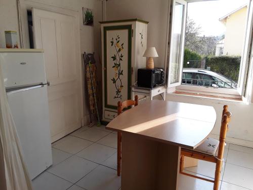 a kitchen with a counter and a refrigerator and a window at La Tanière in Bains-les-Bains