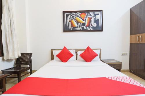 a bedroom with a bed with red pillows at Super Hotel O Mominpur Guest House in Kolkata