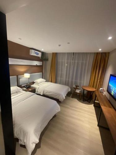 a hotel room with two beds and a flat screen tv at JTOUR Inn Wuhan Textile University in Wuhan
