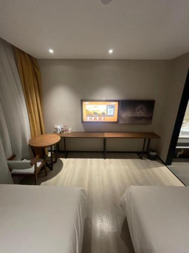 a room with two beds and a tv on the wall at JTOUR Inn Wuhan Textile University in Wuhan