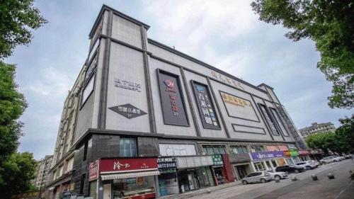a building on the side of a street with cars at JTOUR Inn Wuhan Textile University in Wuhan
