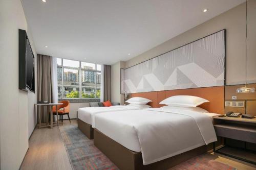 a hotel room with two beds and a television at Borrman Hotel Jinhua Yiwu International Trade Mall in Yiwu