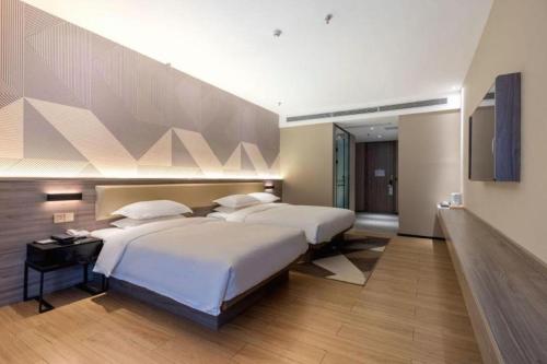 a bedroom with two beds and a flat screen tv at Borrman Hotel Korla Peacock River in Korla