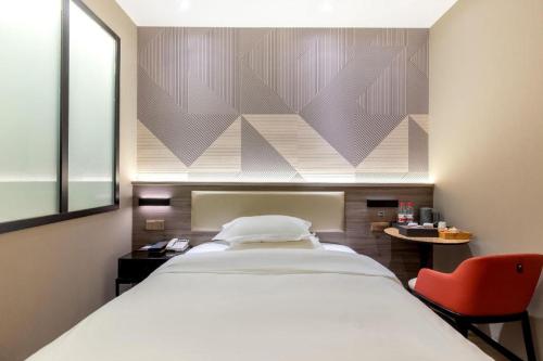 a bedroom with a white bed and a red chair at Borrman Hotel Korla Peacock River in Korla