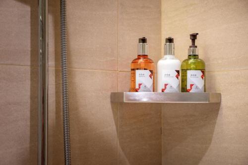 three bottles of alcohol are sitting on a shelf in a shower at Borrman Hotel Korla Peacock River in Korla