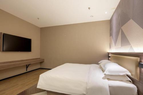 a bedroom with a white bed and a flat screen tv at Borrman Hotel Korla Peacock River in Korla