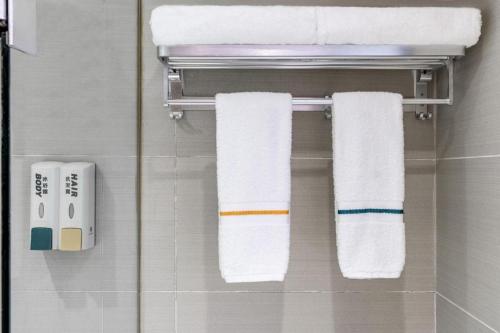 City Comfort Inn Wuhan Zongguan Metro Station في ووهان: حمام مع المناشف معلقة على رف المناشف