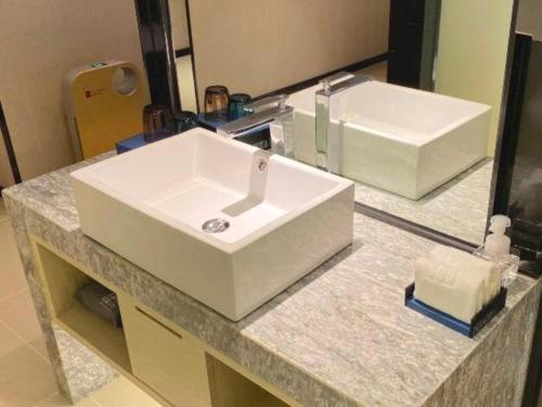 a bathroom counter with a white sink and a mirror at Echarm Hotel Shenzhen World Exhibition and Convention Center in Shenzhen