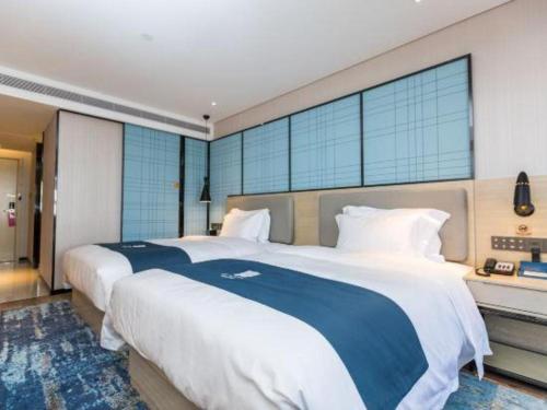 two beds in a hotel room with large windows at Echarm Hotel Shenzhen World Exhibition and Convention Center in Shenzhen