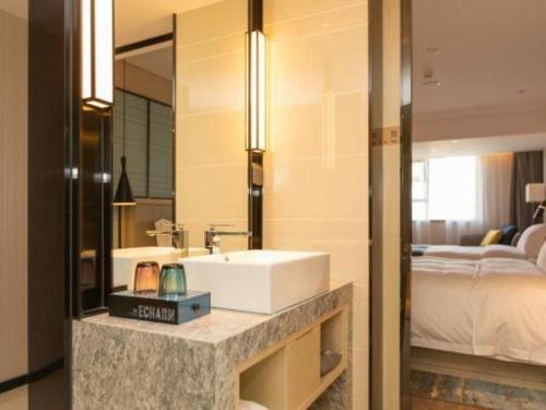 a bathroom with a sink and a bed and a mirror at Echarm Hotel Shenzhen World Exhibition and Convention Center in Shenzhen