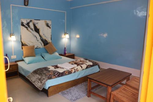een slaapkamer met een bed met een blauwe muur bij Tirthan Living Green Home Stays in Banjār