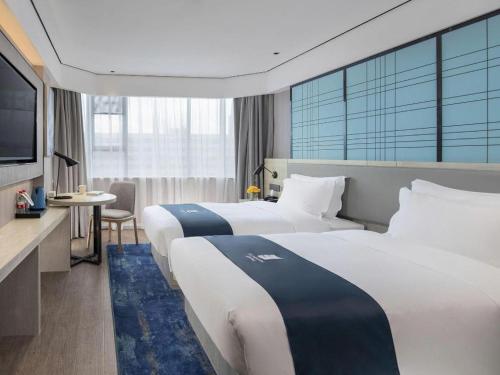 a hotel room with two beds and a flat screen tv at Echarm Hotel Shenzhen International Exhibition Center Fuyong in Shenzhen