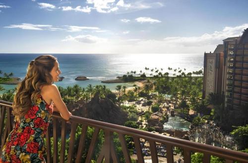a woman standing on a balcony looking at the ocean at Aulani, Disney Vacation Club Villas in Kapolei