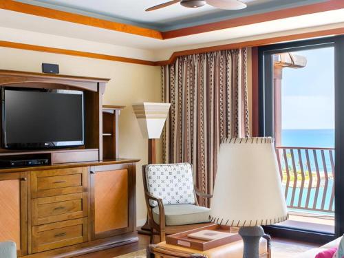 a living room with a television and a chair at Aulani, Disney Vacation Club Villas in Kapolei